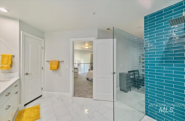 ensuite bathroom with walk in shower, vanity, baseboards, marble finish floor, and ensuite bathroom