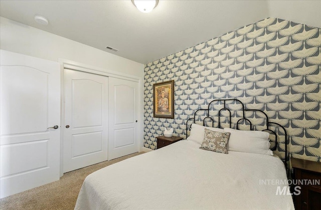 bedroom featuring wallpapered walls, visible vents, light carpet, and a closet