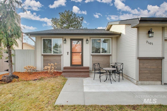 doorway to property with a lawn and a patio