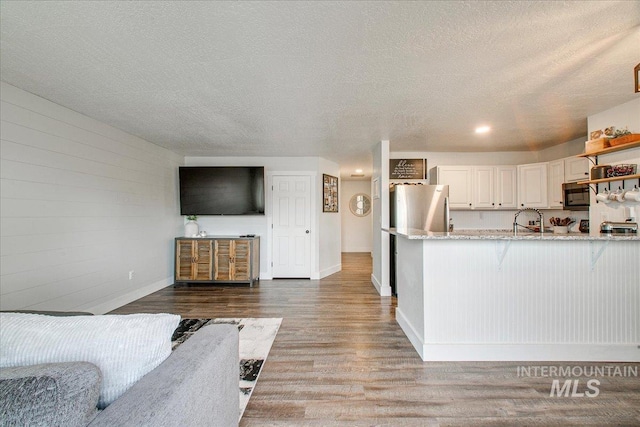 living room featuring hardwood / wood-style flooring, sink, and a textured ceiling