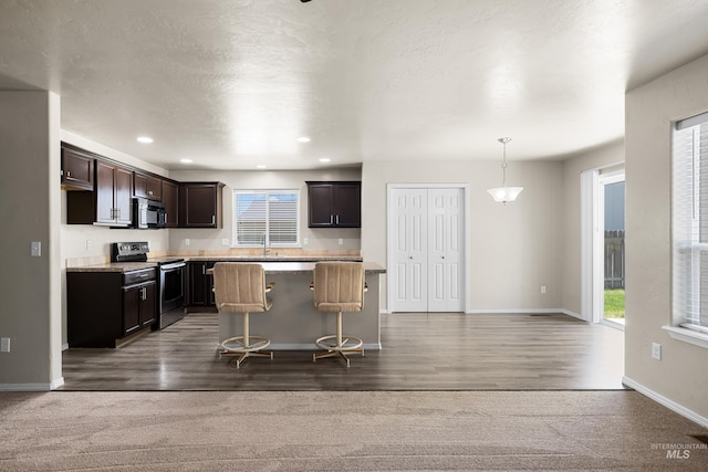 4618 Braeburn Ave, Caldwell, ID 83607 - kitchen featuring stainless steel electric stove, black microwave, light countertops, dark brown cabinetry, and a kitchen bar