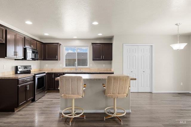 4618 Braeburn Ave, Caldwell, ID 83607 - kitchen with stainless steel electric stove, dark brown cabinets, black microwave, wood finished floors, and a kitchen island