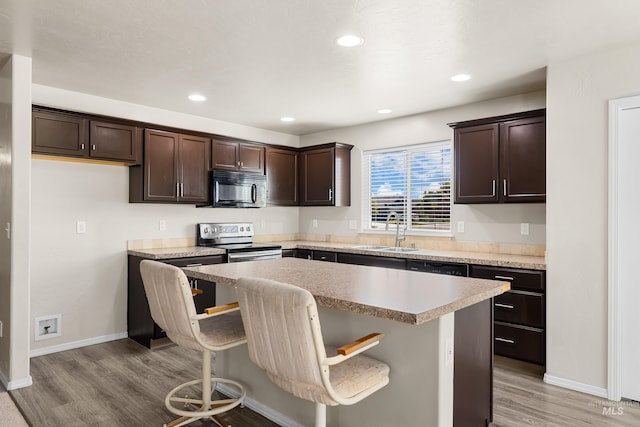 4618 Braeburn Ave, Caldwell, ID 83607 - kitchen featuring electric range, black microwave, dark brown cabinets, light wood-type flooring, and a center island