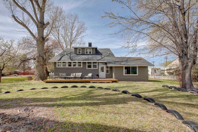 rear view of property with a chimney, a wooden deck, fence, and a lawn