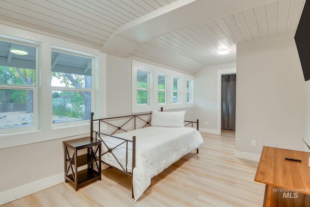 bedroom featuring baseboards, lofted ceiling, and light wood finished floors