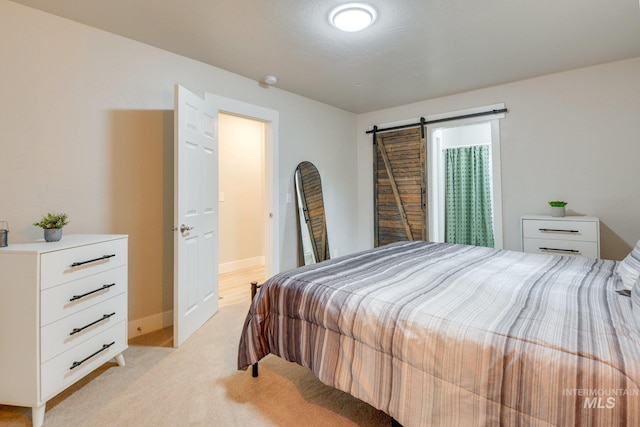bedroom with a barn door, baseboards, and light colored carpet