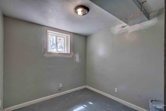 unfurnished room with baseboards and unfinished concrete flooring