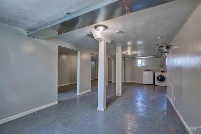below grade area with separate washer and dryer, baseboards, and a textured ceiling