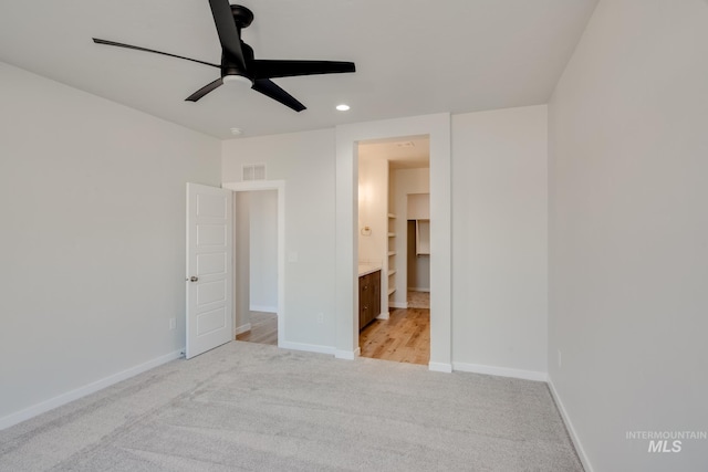 unfurnished bedroom featuring a walk in closet, ceiling fan, light carpet, and a closet