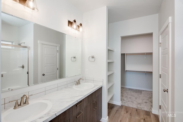 bathroom featuring vanity, built in shelves, a shower with door, and wood-type flooring