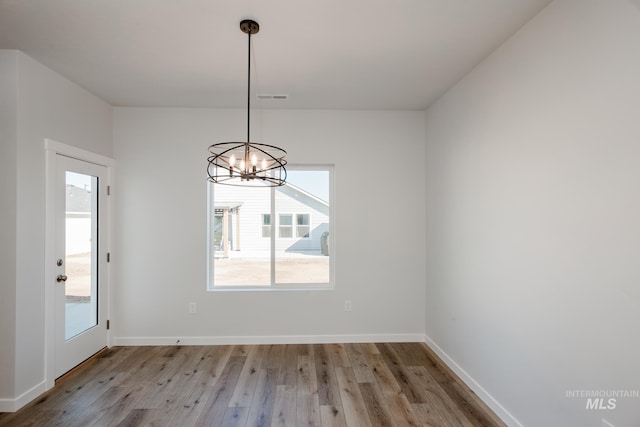 unfurnished dining area featuring a notable chandelier and light wood-type flooring