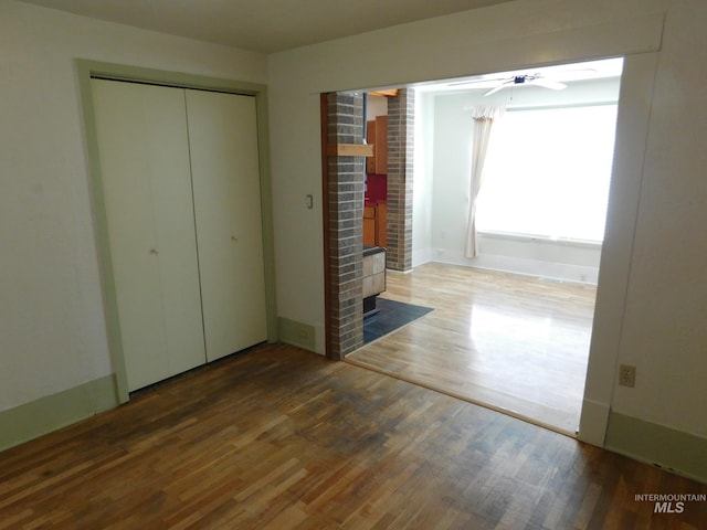 unfurnished bedroom featuring wood finished floors, a closet, and baseboards