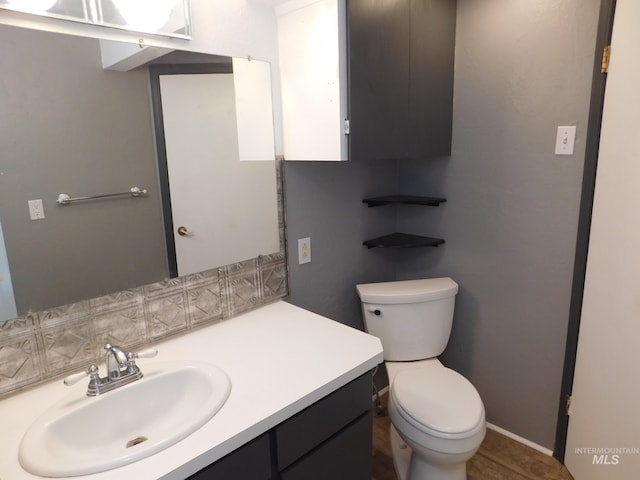 bathroom with vanity, baseboards, and toilet