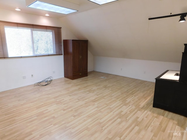 bonus room featuring light wood-style flooring, recessed lighting, baseboards, and lofted ceiling with skylight