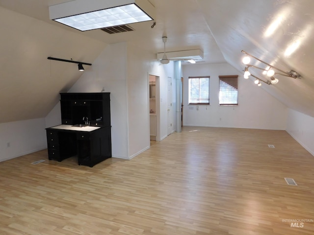 additional living space featuring light wood-style floors, visible vents, baseboards, and vaulted ceiling
