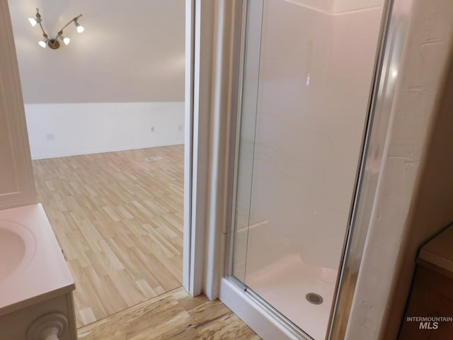 bathroom featuring vanity, a stall shower, and wood finished floors