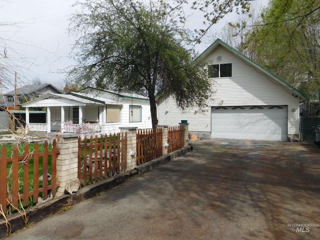 view of front of house featuring a porch, driveway, an attached garage, and a fenced front yard