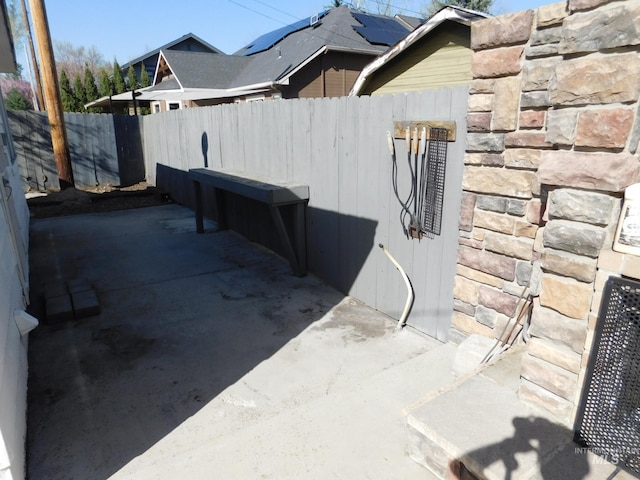 view of side of home featuring a fenced backyard and stone siding