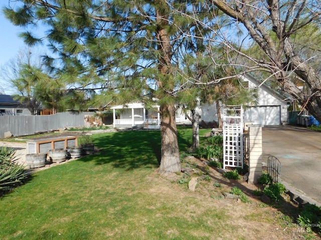 view of yard featuring a garage, driveway, an outdoor structure, and fence