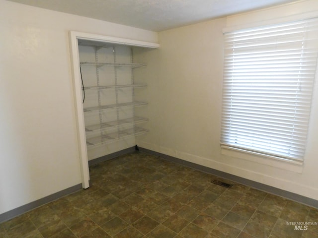 unfurnished room with visible vents, baseboards, and dark floors