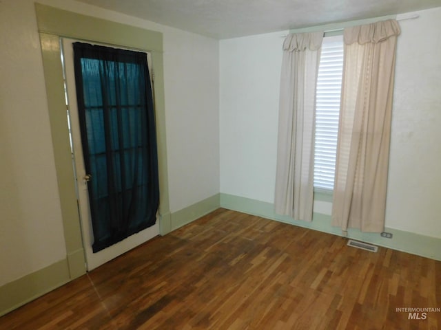 unfurnished room with wood finished floors and visible vents
