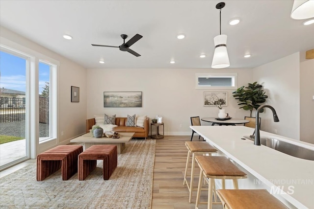 living area with recessed lighting, a ceiling fan, light wood-type flooring, and baseboards