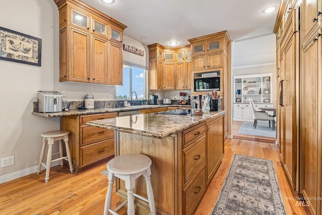 4459 E Deer Flt, Kuna, ID 83634 - kitchen with stainless steel microwave, light wood finished floors, a kitchen island, light stone counters, and a breakfast bar