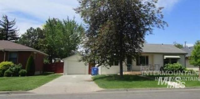 view of front of property featuring concrete driveway, an outdoor structure, and a front lawn