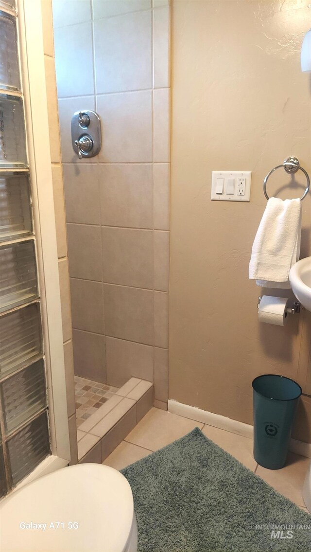 bathroom with toilet, tile patterned floors, baseboards, and a stall shower