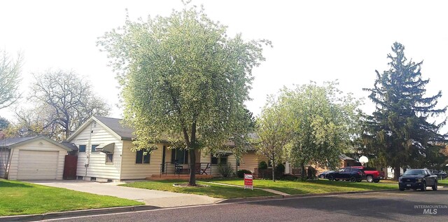 view of front of home with concrete driveway, an outbuilding, a front lawn, and a garage