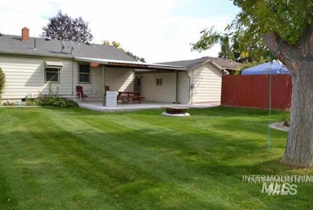 back of house featuring a patio area, an outdoor fire pit, a yard, and fence