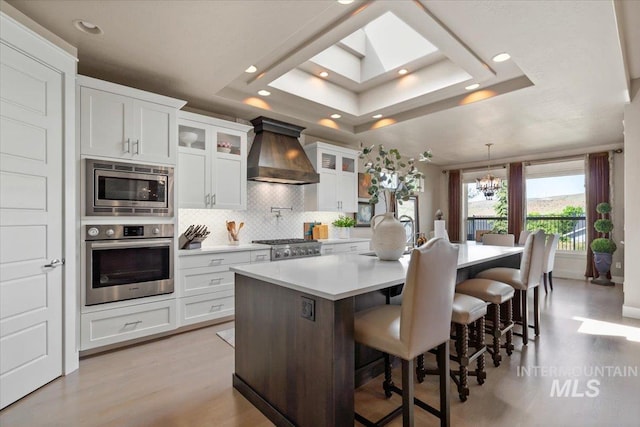 4772 W Barnview Dr, Boise, ID 83614 - kitchen with appliances with stainless steel finishes, custom range hood, a tray ceiling, tasteful backsplash, and light countertops