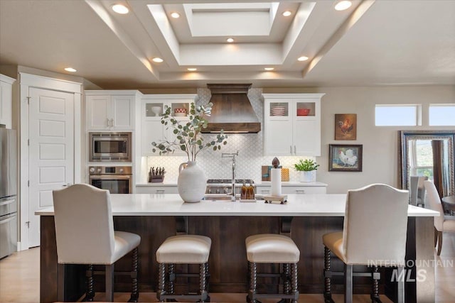 4772 W Barnview Dr, Boise, ID 83614 - kitchen with appliances with stainless steel finishes, premium range hood, tasteful backsplash, light countertops, and a center island with sink