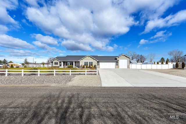 view of front of property with a fenced front yard, concrete driveway, and a garage