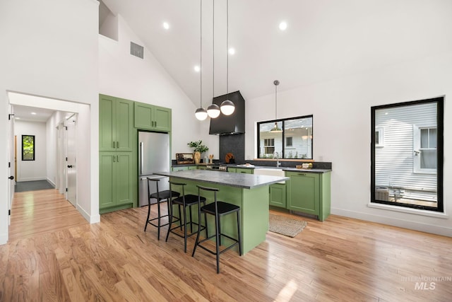 1435 N Garden, Boise, ID 83706 - kitchen featuring green cabinetry, appliances with stainless steel finishes, wall chimney exhaust hood, a breakfast bar area, and high vaulted ceiling