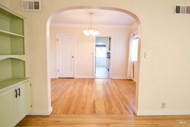 corridor featuring light hardwood / wood-style floors, an inviting chandelier, and ornamental molding