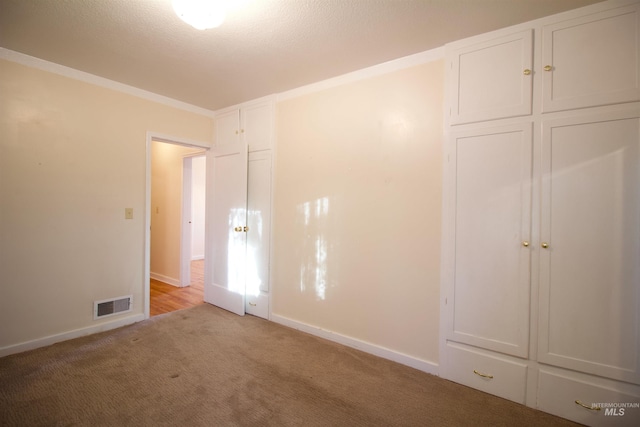 unfurnished bedroom with light colored carpet, a closet, and ornamental molding