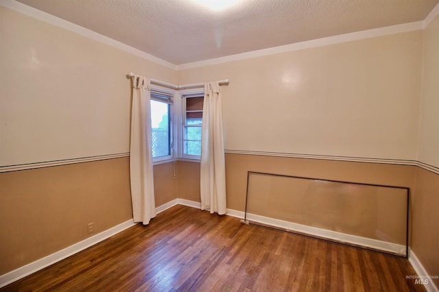 spare room featuring dark hardwood / wood-style flooring, ornamental molding, and a textured ceiling