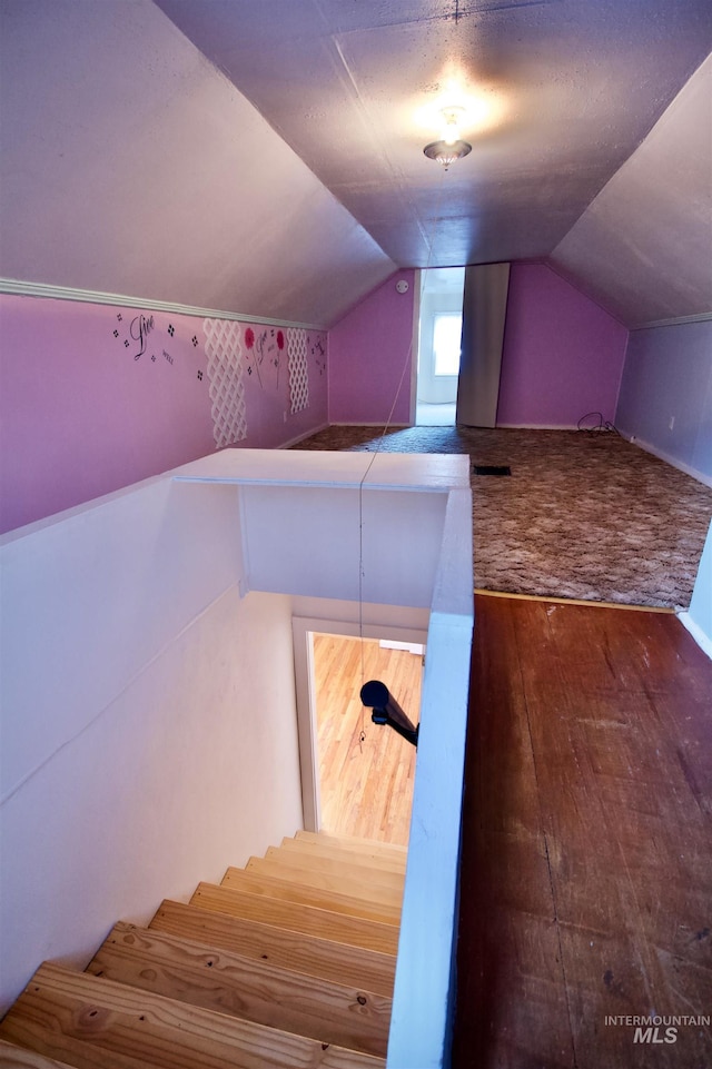 stairs featuring wood-type flooring, lofted ceiling, and a textured ceiling