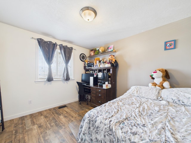 bedroom featuring dark wood-type flooring, baseboards, visible vents, and a textured ceiling