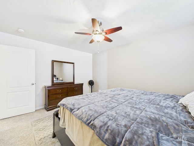 bedroom with light carpet, a textured ceiling, and a ceiling fan