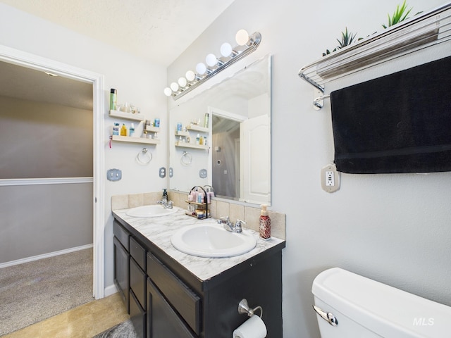 full bath featuring a sink, baseboards, toilet, and double vanity