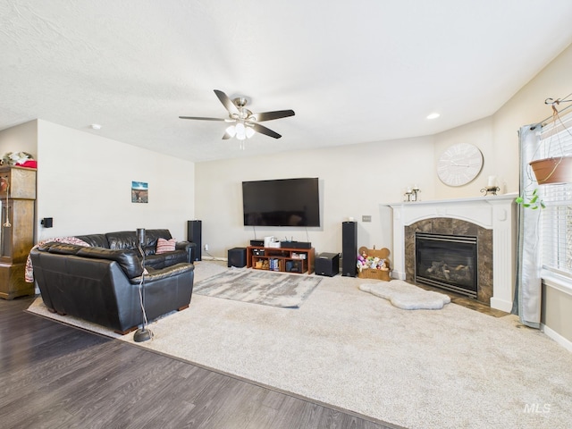 living area with baseboards, a ceiling fan, wood finished floors, and a fireplace