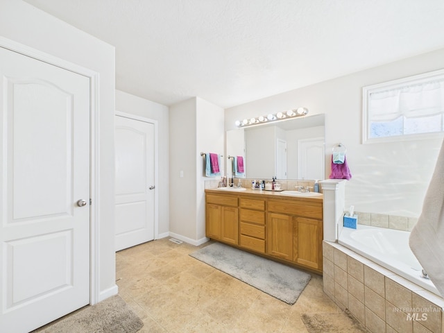 full bathroom featuring double vanity, a bath, baseboards, and a sink