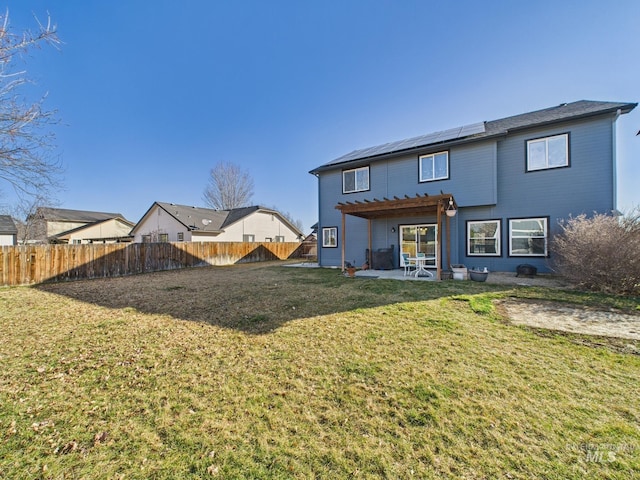 rear view of property featuring solar panels, a patio area, a lawn, and a fenced backyard