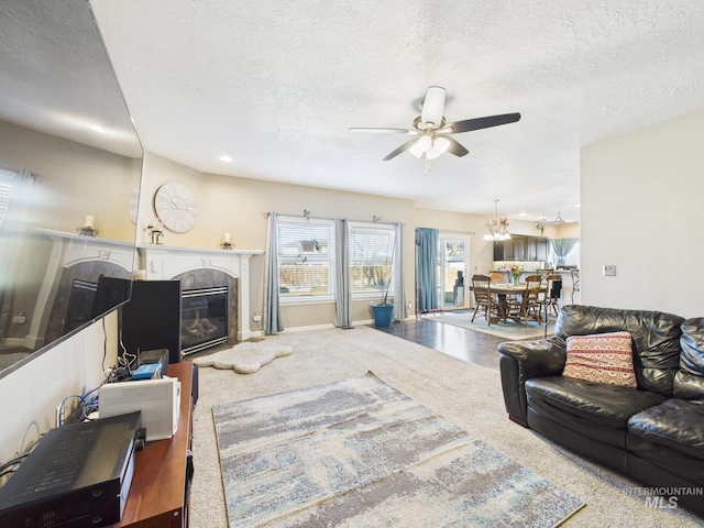 living area with a premium fireplace, baseboards, a textured ceiling, and a ceiling fan