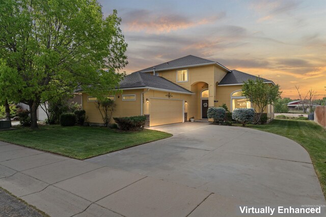 traditional-style house featuring a garage, a lawn, driveway, and a shingled roof
