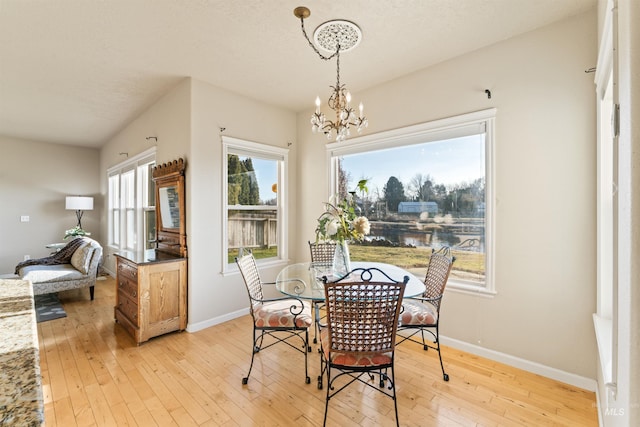 dining area featuring a chandelier, light wood-type flooring, and baseboards