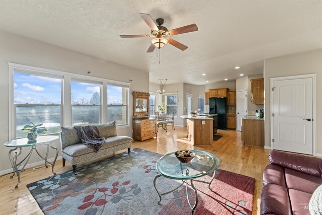 living area featuring light wood finished floors, a ceiling fan, a chandelier, recessed lighting, and baseboards