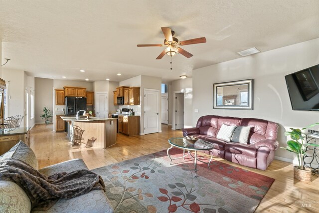 living room featuring ceiling fan, light wood-style flooring, baseboards, and recessed lighting